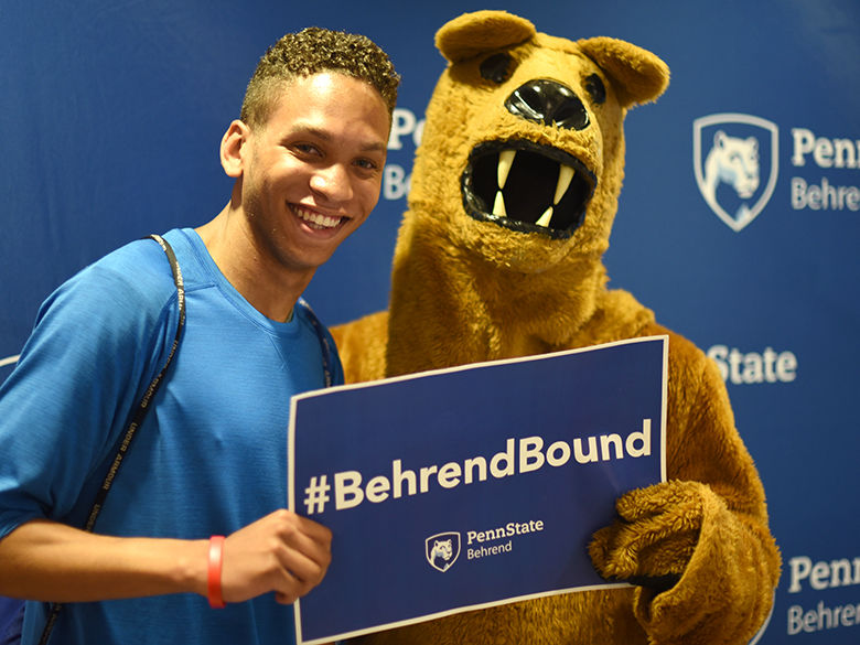 Student stands with Behrend Lion with sign that says #BehrendBound
