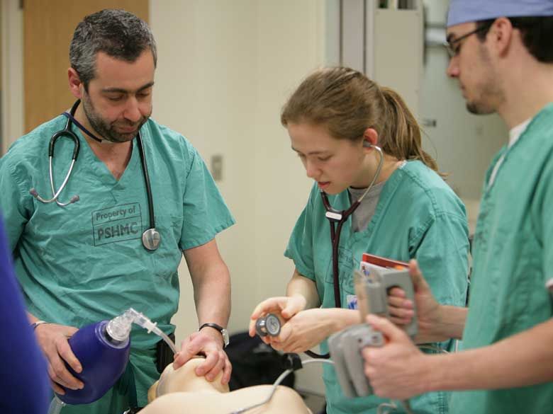 Two students learn pre-medical skills from a faculty member at Penn State Behrend.