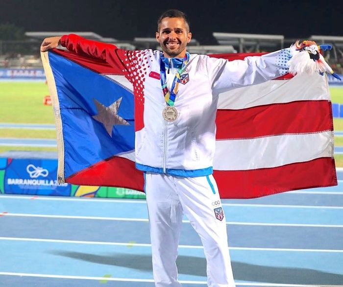 Steeplechase racer Ricardo Estremera poses with the Puerto Rican flag on his shoulders.