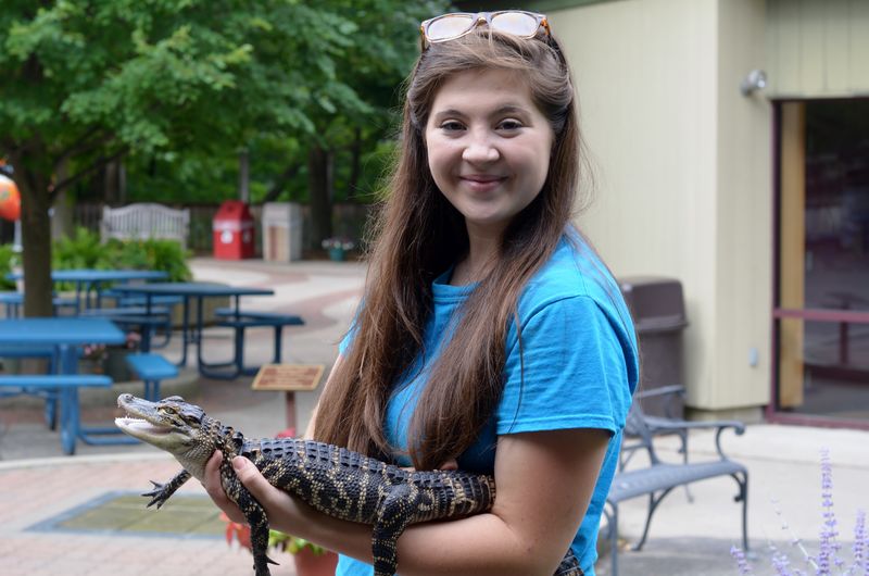 A Penn State Behrend student holds a reptile at the Erie Zoo.