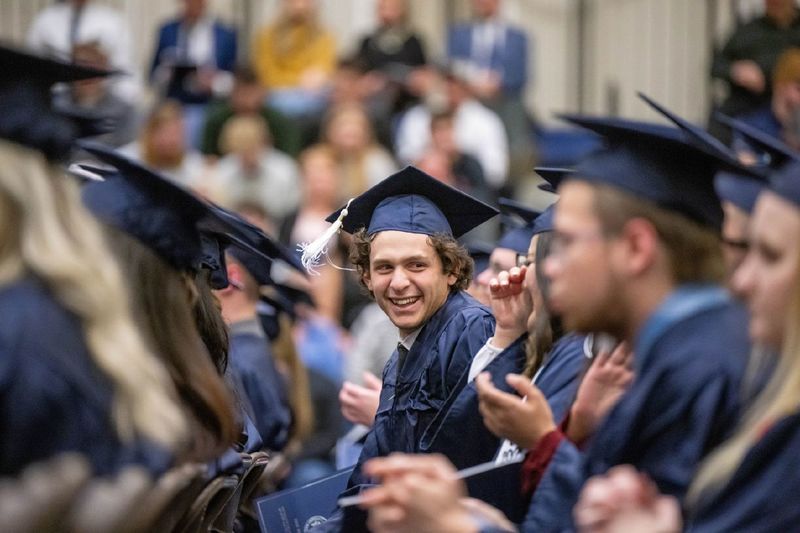 A new graduate turns to look at a classmate during Penn State Behrend's fall 2022 commencement program.