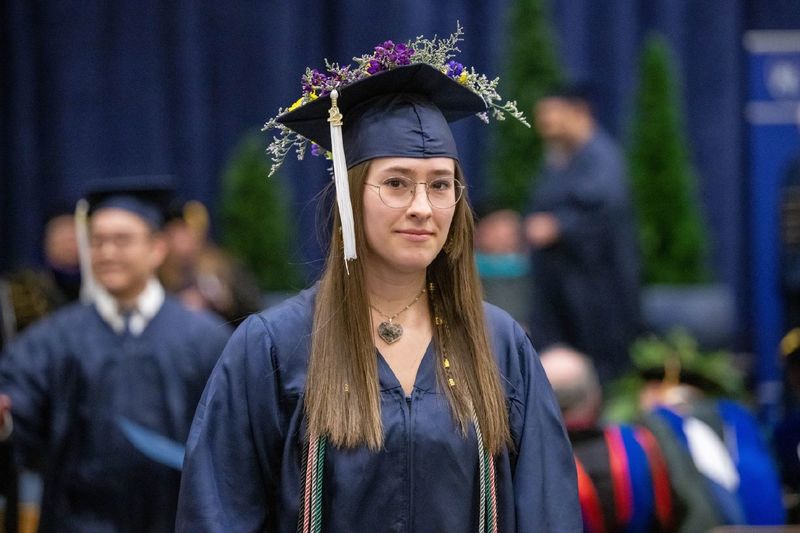 A new graduate walks back to her seat after receiving her degree at Penn State Behrend's fall 2022 commencement program.