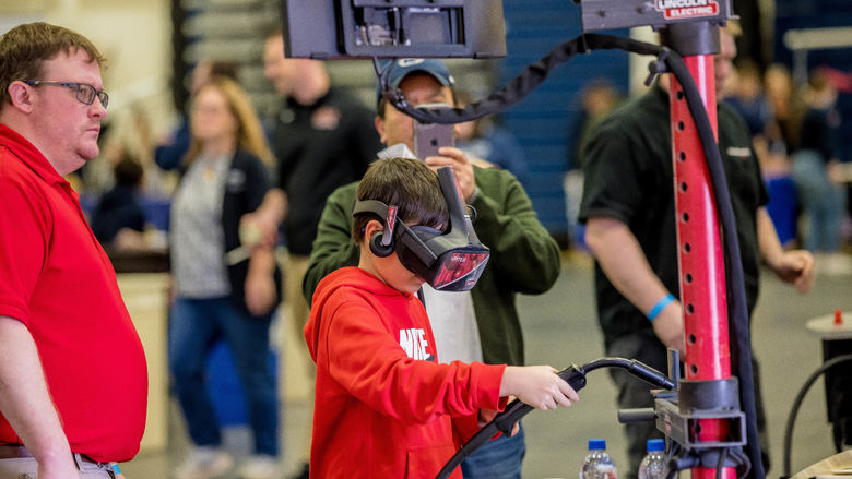 A boy tries a hands-on virtual welding simulation at the Penn State Behrend STEAM Fair.