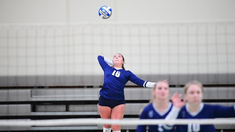 A Penn State Behrend volleyball player jumps while serving the ball.