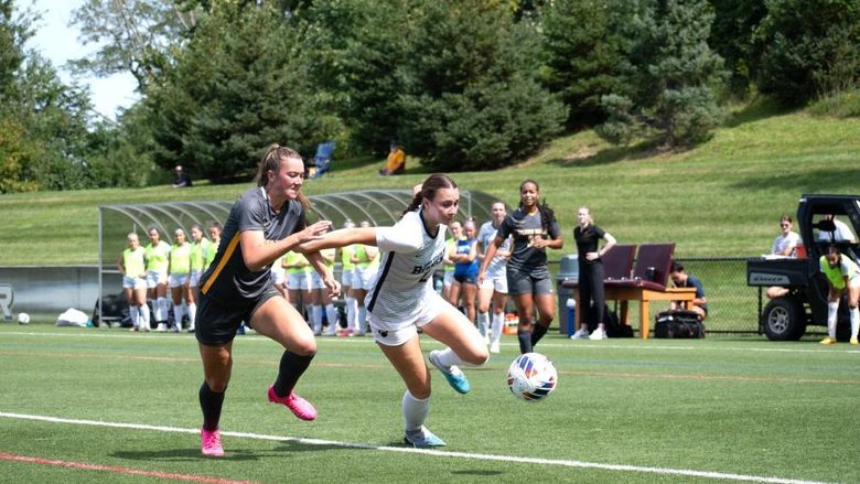 A Penn State Behrend women's soccer player runs past a defender.
