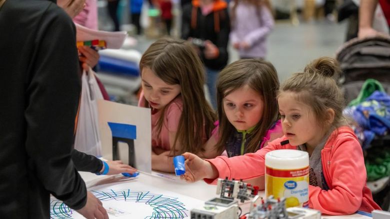 Three girls experiment with a robotic pen at Penn State Behrend's annual STEAM Fair.