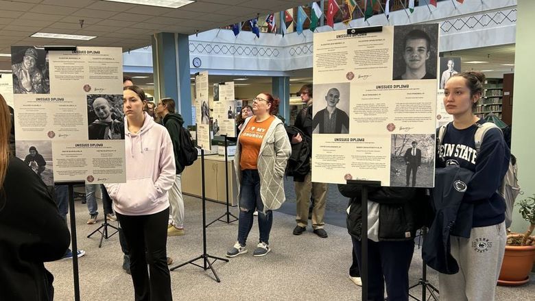 Students look at posterboards with information about victims of the war in Ukraine.
