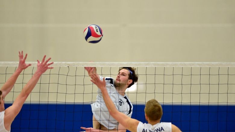 A Penn State Behrend volleyball player spikes the ball.