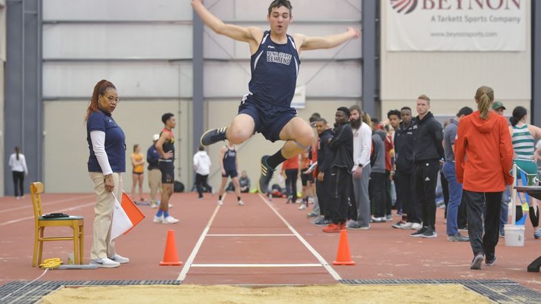 A Penn State Behrend athlete competes in the long jump at an indoor meet.