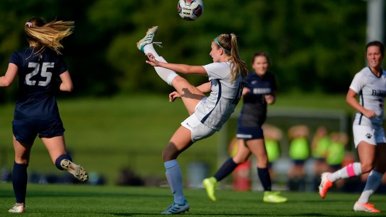 A Penn State Behrend soccer player kicks the ball over her head.