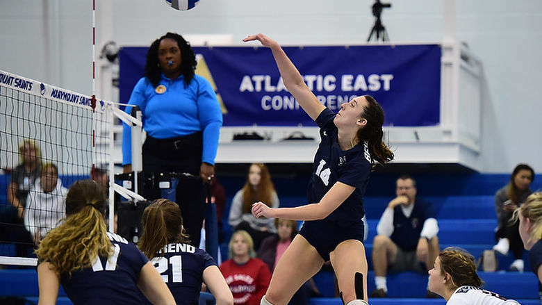 A female Penn State Behrend volleyball player spikes the ball.