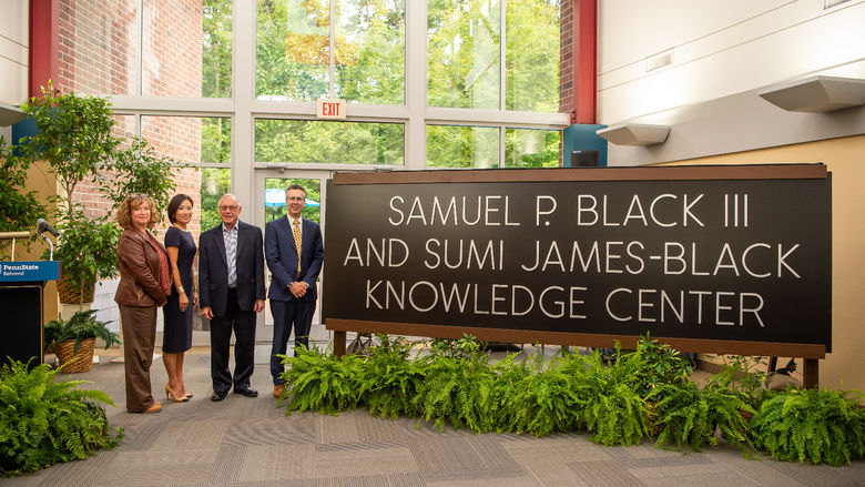 Four officials stand near the new sign for the Samuel P. Black III and Sumi James-Black Knowledge Center