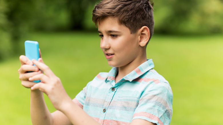 A boy holds a smartphone while completing a virtual scavenger hunt.