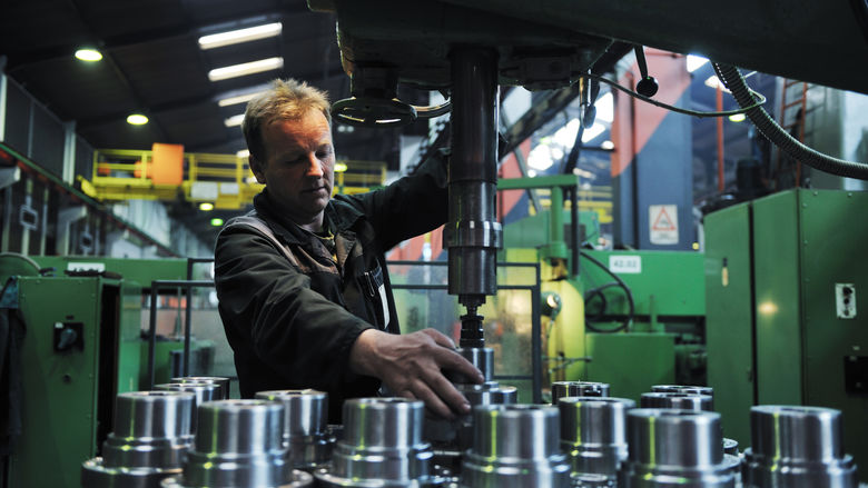 A man operates machinery in an advanced manufacturing environment.