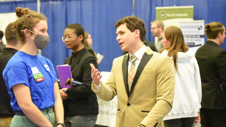 A student gestures while talking with a recruiter at the Penn State Behrend spring Career and Internship Fair.