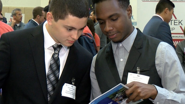 Two male students peruse a booklet.