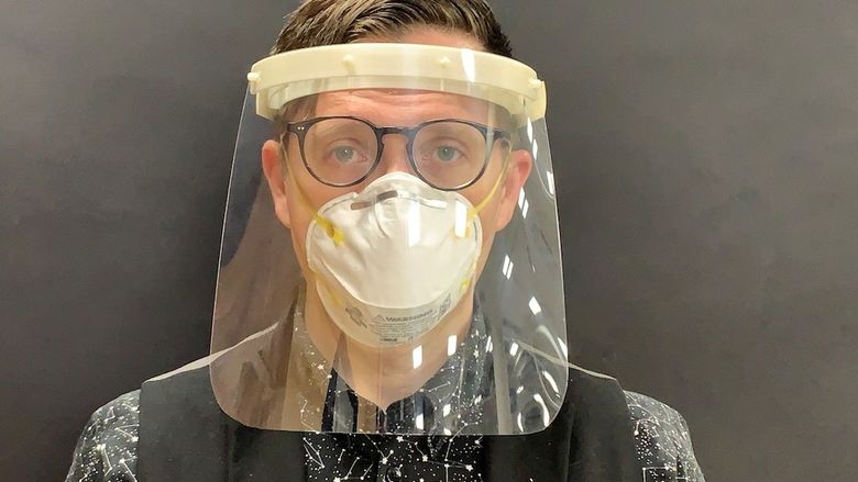 A man models a plastic medical face shield.
