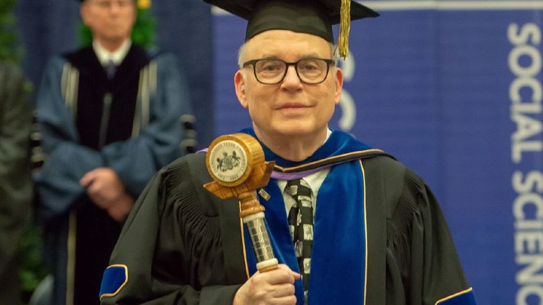 John Gamble carries the Penn State Behrend mace during a college commencement program.