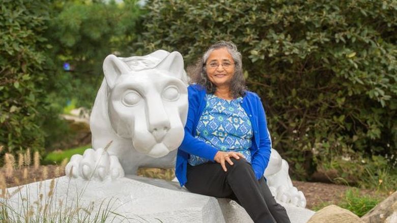 Alumna Nishi Gupta sits at the Nittany Lion shrine at Penn State Behrend