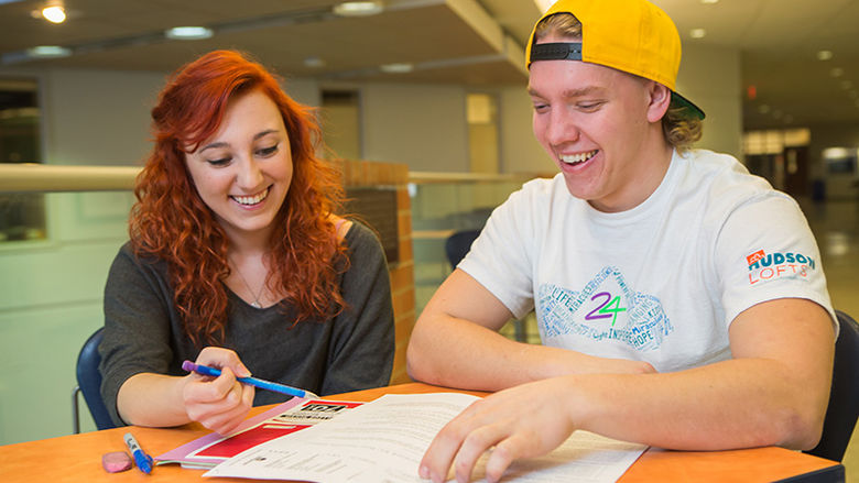 A student tutor works with a student at a table.