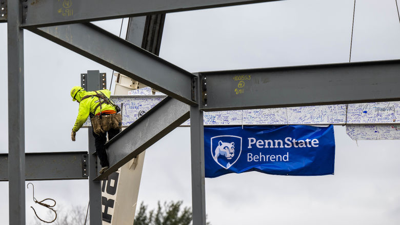A steelworker sets a 32-foot beam into place at the site of Penn State Behrend's new Erie Hall.