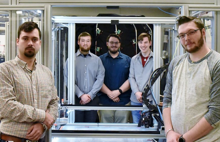 Five students pose near a large-scale 3D printer in Penn State Behrend's Innovation Commons lab.