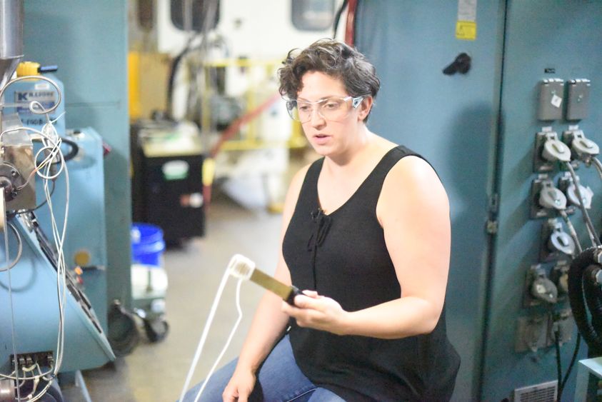 Cleveland-based sculptor Lauren Herzak-Bauman manipulates plastic while working in Penn State Behrend's plastics processing lab.