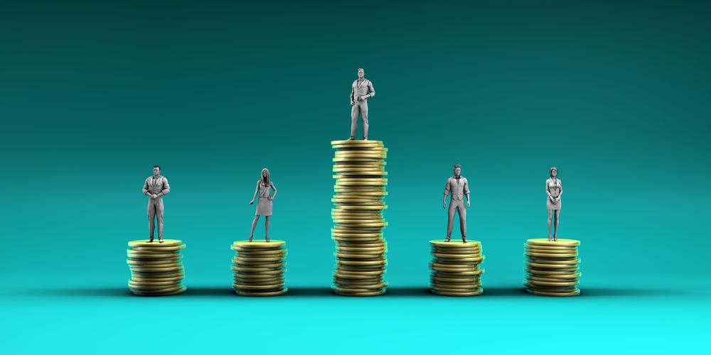 A series of figurines rest atop coins stacked to various heights to illustrate income inequality.