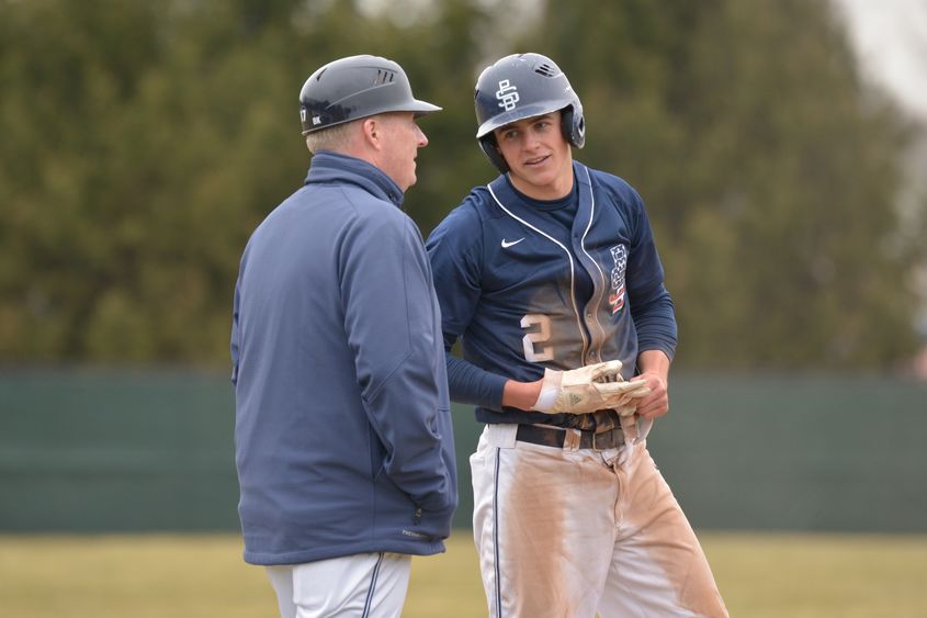 Penn State Behrend baseball player Scott Sada talks with his coach while on base.