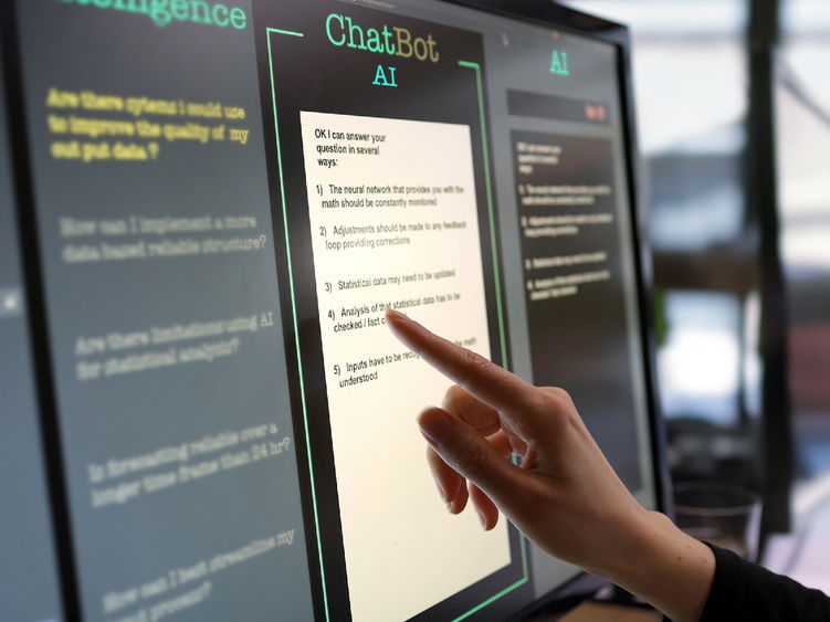 A hand points to a touchscreen displaying a response from an AI chatbot