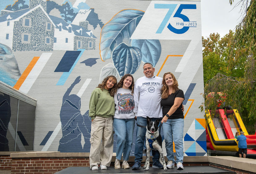 Guests pose in front of the new "Behrend Pride" mural at Penn State Behrend.