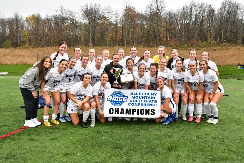 The Penn State Behrend women's soccer team poses with the AMCC championship banner.