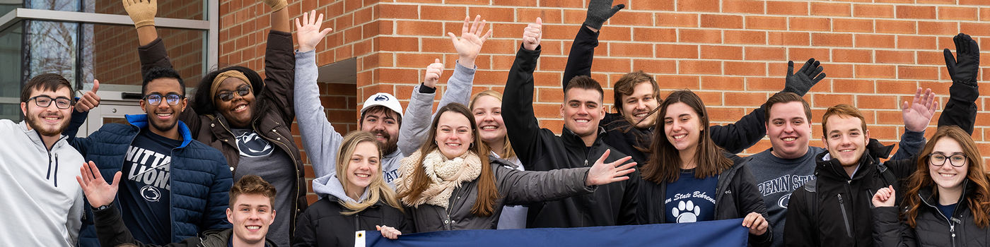 A group of Behrend students waving while posing outside Burke Center.