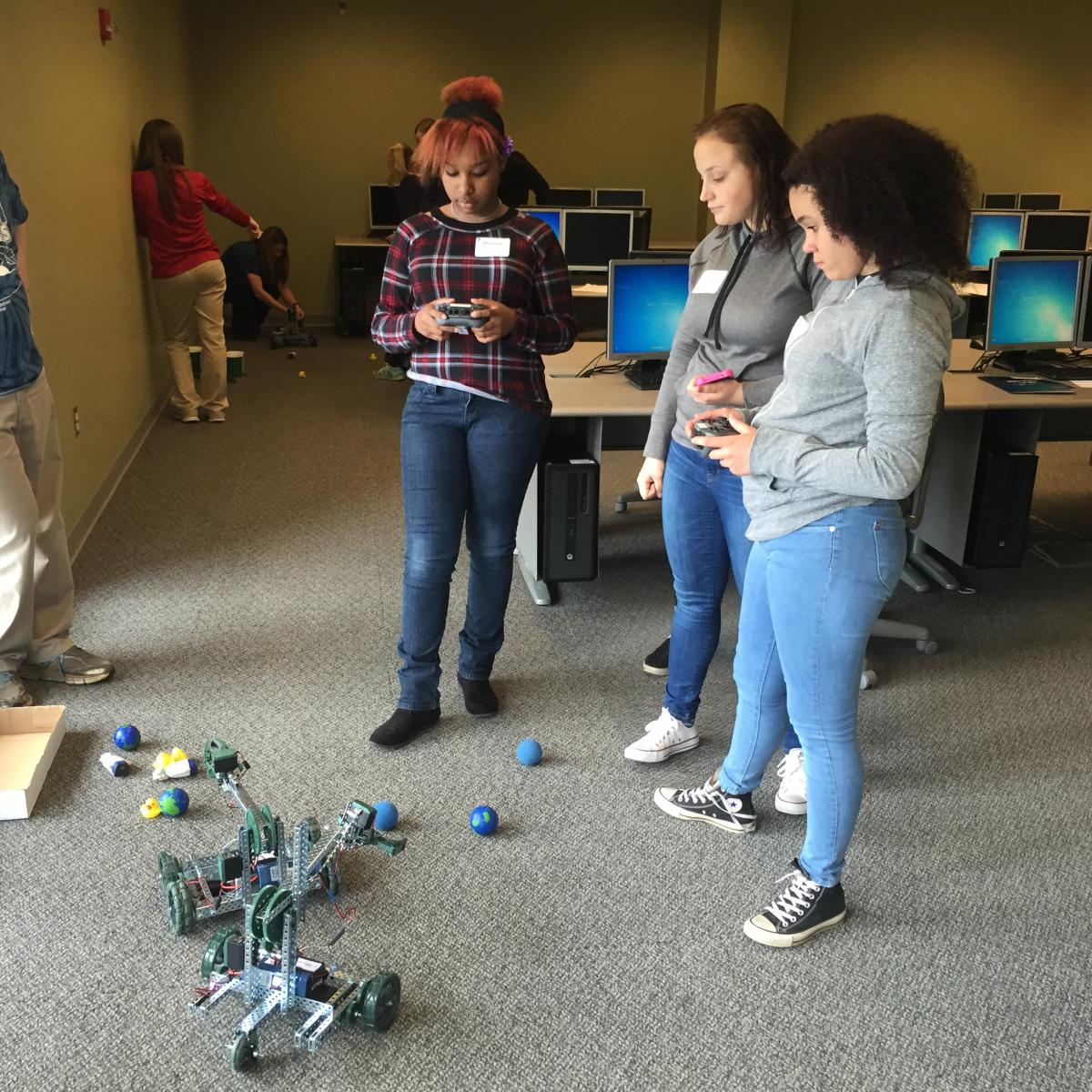 Asialynn Noyer, left, and Mariah Lucas, far right, both control VEX robots while Ashja Raucci, center, looks on. 
