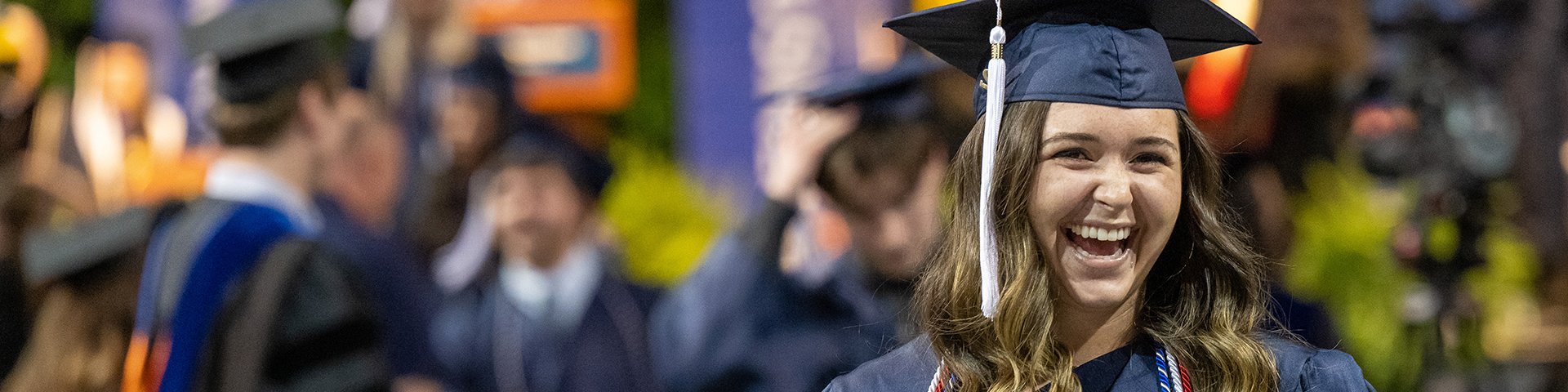 A female graduate smiles after crossing the stage at commencement