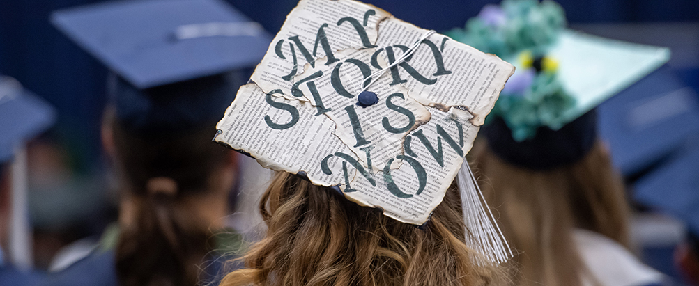 Student wearing mortarboard decorated to say My Story Is Now