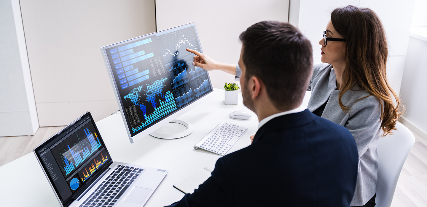 A woman and a man studying financial charts on a computer