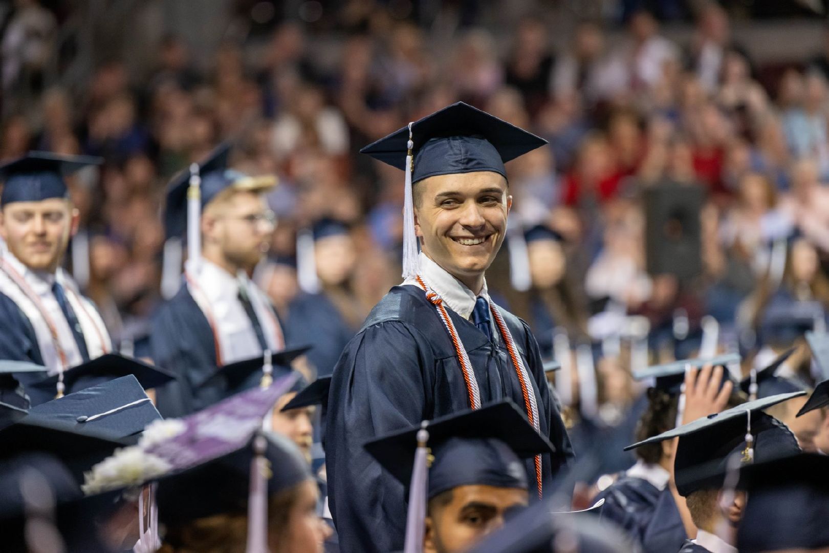 A student stands and smiles at Penn State Behrend's spring 2022 commencement program.