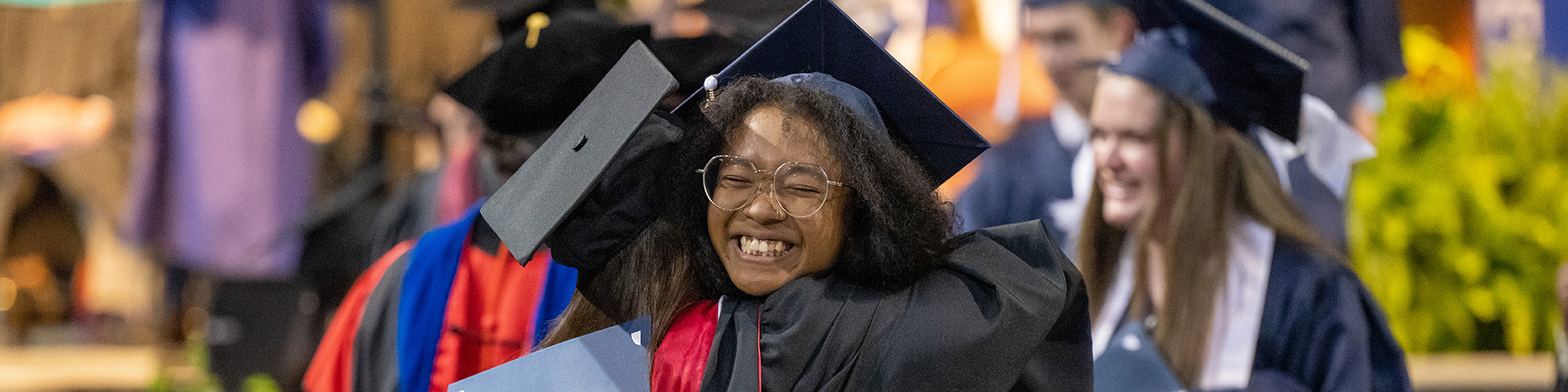 A graduate hugs a professor after receiving her diploma at Behrend commencement