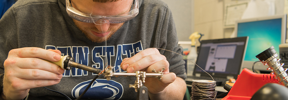 A Penn State Behrend student working on electrical components.