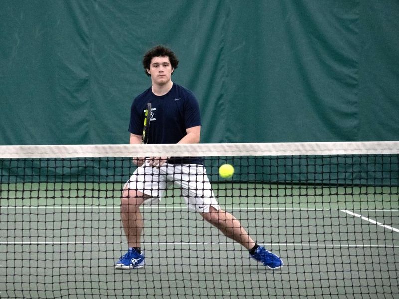 A member of the Penn State Behrend men's tennis team prepares to hit a ball.