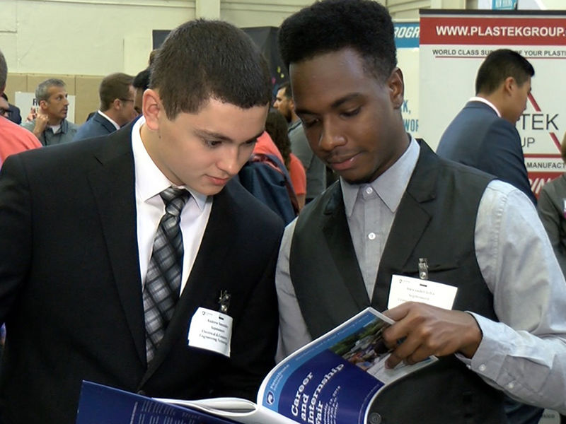 Two male students peruse a booklet.