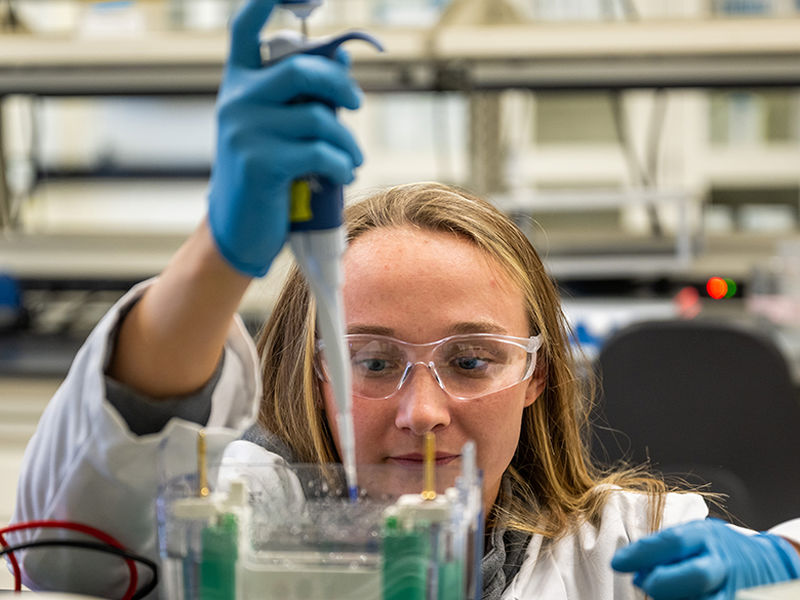 Female student performs science experiment.