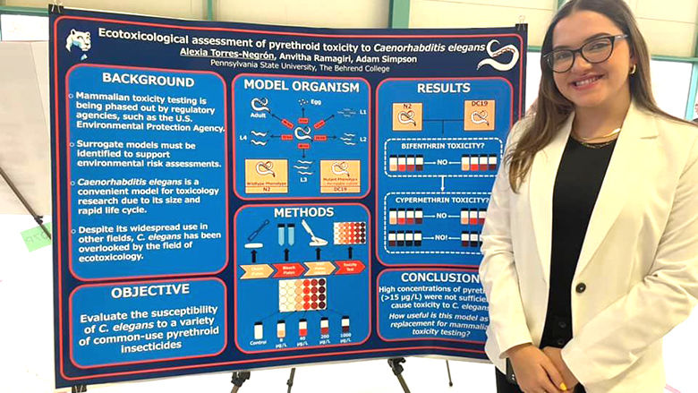 Female student stands next to research poster outlining a project.