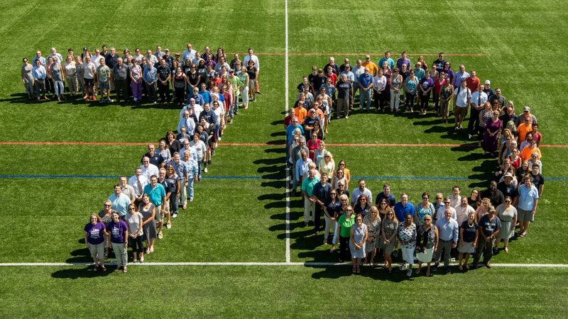 Faculty, staff and students assemble on a Penn State Behrend field in the formation of a 70.