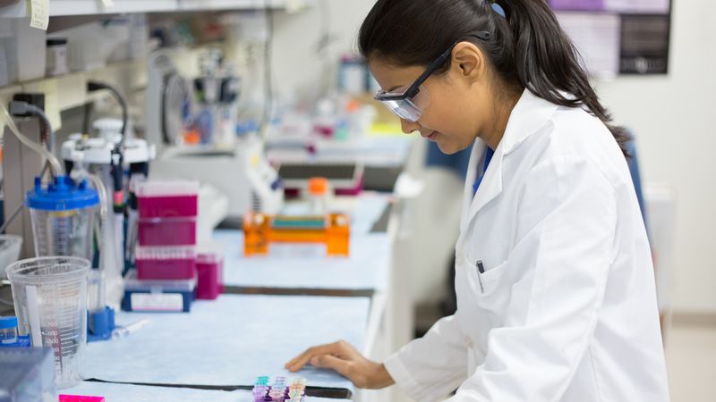 A researcher wearing safety glasses works in a biomedical lab.