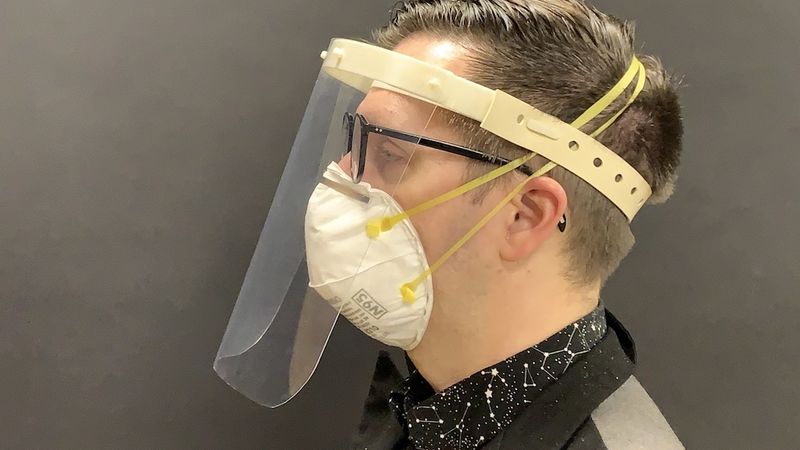 A product developer models a medical face shield for use in COVID-19 environments.