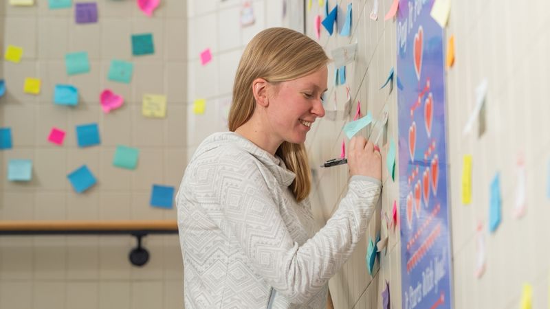 Penn State Behrend alumna Ashlyn Kelly writes on a post-it note in the Reed Union Building stairwell.