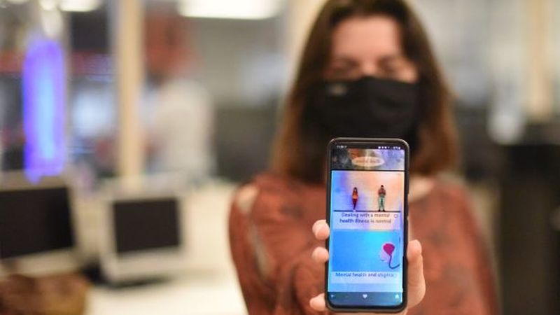 A Penn State Behrend student holds up a cell phone showing the new Serene mental-health and mindfulness app.