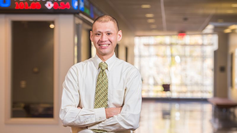 A Penn State Behrend professor stands outside the financial trading lab in Burke Center.